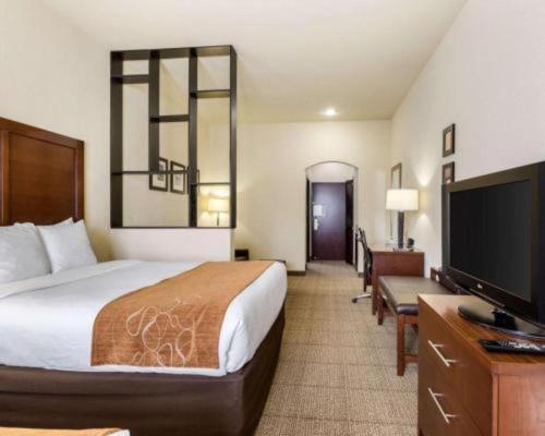 a hotel room with a bed and a flat screen tv at Comfort Suites near NASA - Clear Lake in Webster