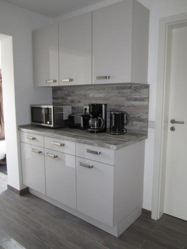 a kitchen with white cabinets and two microwaves at Lieblingsplatz in Kappeln