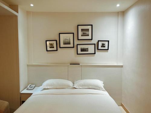 a bedroom with a bed with four pictures on the wall at Wemeet Hotel in Pingtung City