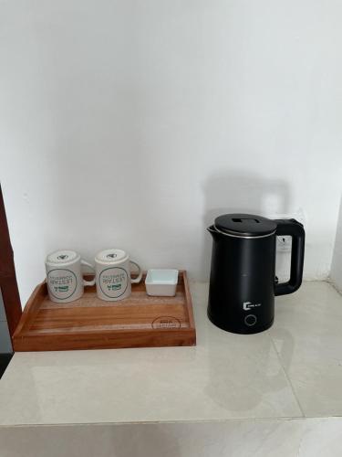 cafetera y 3 tazas en una bandeja de madera en Lestari Homestay Jimbaran, en Jimbaran