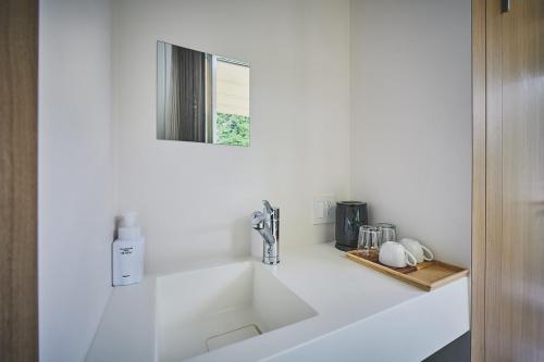 a white sink in a bathroom with a mirror at Sakanaya Stay in Kona