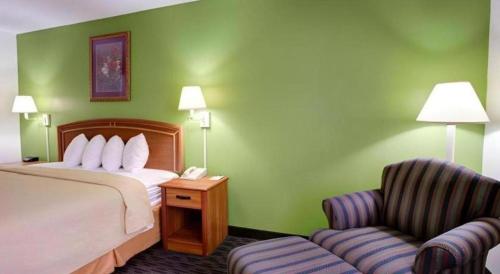 a hotel room with a bed and a chair at Quality Inn & Suites Airport in Austin