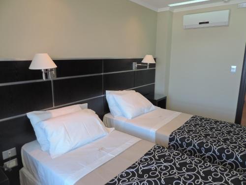 a hotel room with two beds and two lamps at Apart Belgrano in Posadas