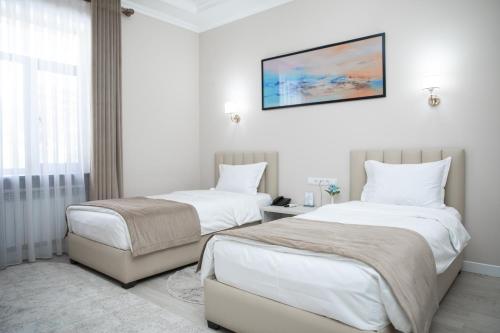 two beds in a room with white walls at Turon Lux Hotel in Samarkand