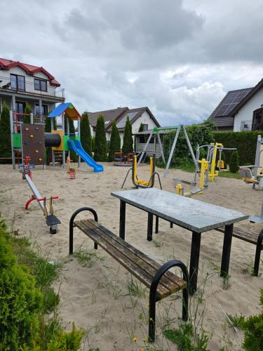 a playground with a picnic table and swings at Bursztynek in Gąski