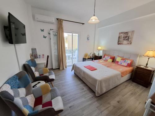 a bedroom with a bed and a tv and chairs at Panayota Apartments in Kassiopi