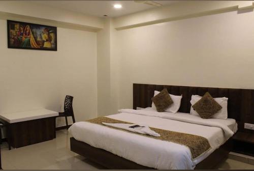 a bedroom with two beds and a desk in it at Hotel Rose inn in Surat