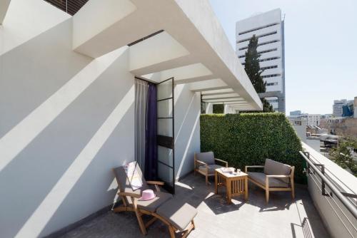 a balcony with chairs and a table on a building at Lily & Bloom Boutique Hotel in Tel Aviv