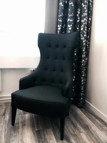 a black chair in a room with a window at STF Hotell Rum Oscar in Oskarshamn