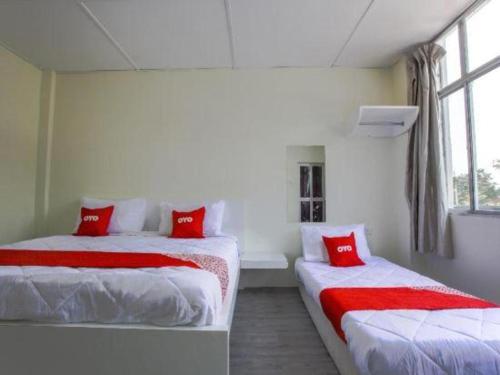 two beds in a room with red pillows at OYO 822 Zande Motel Kuala Selangor in Kuala Selangor