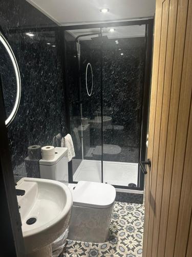 a bathroom with a shower and a toilet and a sink at The Goodrington Sands- Apart Hotel in Paignton