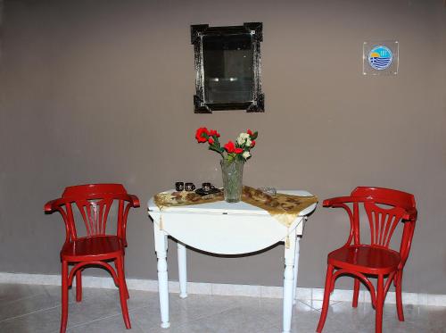 a table with two red chairs and a vase with flowers on it at Johny's Studios in Prinos