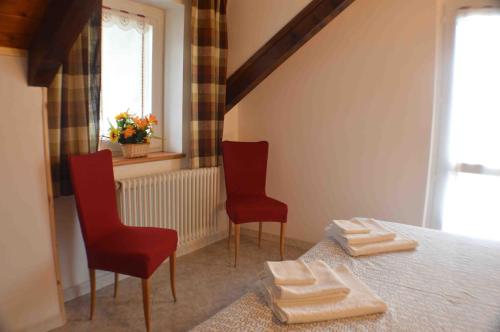 een slaapkamer met 2 stoelen en een bed met handdoeken bij Residence Arvinei in Malesco