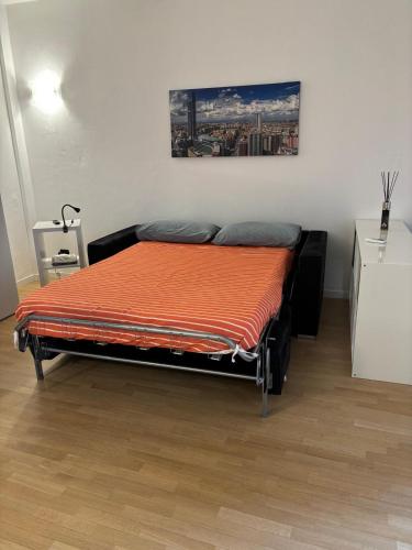 a bedroom with a bed with an orange blanket at In centro da Ale in Seregno