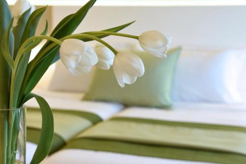 a vase filled with white flowers sitting next to a couch at Athens Avenue Hotel in Athens