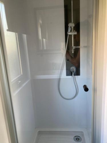 a shower with a glass door with a shower head at Mobil Home 6 personnes in Biscarrosse