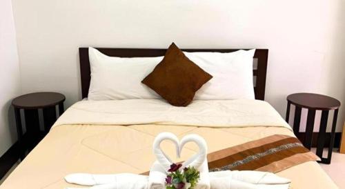 a bed with two white towels and two wedding shoes at Rueangrat Hotel in Ranong