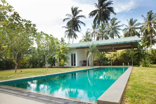 une piscine devant une maison avec des palmiers dans l'établissement PJ's, à Hikkaduwa