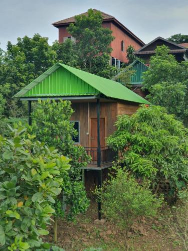 a wooden house with a green roof and trees at Banlung Mountain View Treks & Tours in Banlung