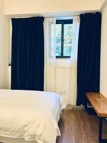 a bedroom with blue curtains and a bed and a table at Xiamen Gulangyu Heitan Hotel in Xiamen