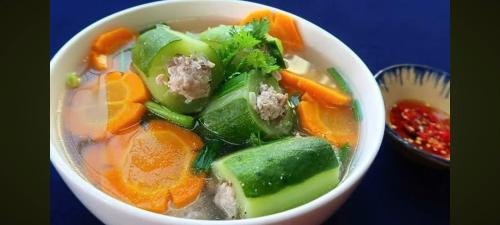a bowl of soup with carrots and other vegetables at MOTEL Đồng Khởi in Giồng Tú Ðiền