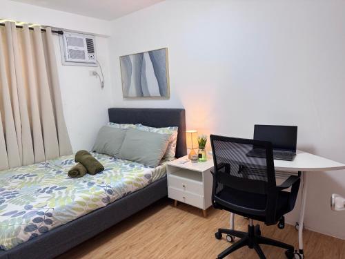 a bedroom with a bed and a desk with a laptop at Lian's Haven at Arezzo Place Davao in Davao City