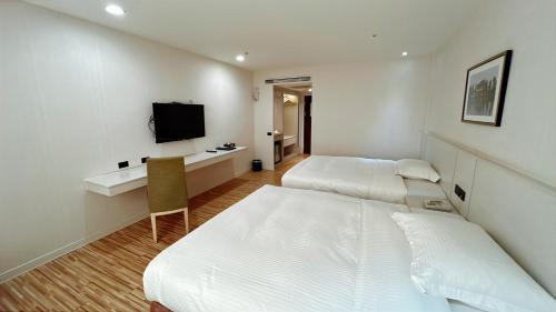a hotel room with two beds and a television at Wemeet Hotel in Pingtung City