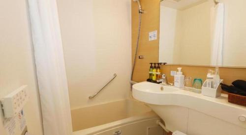 a bathroom with a sink and a tub and a mirror at KEIKYU EX INN Tokyo Nihombashi in Tokyo