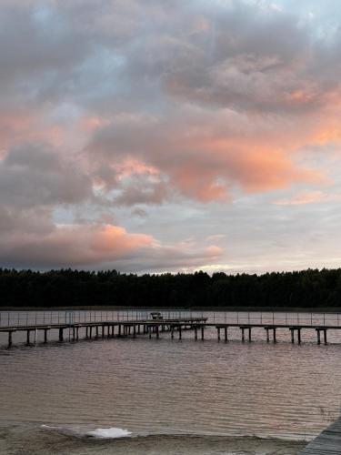 a pier on a lake with a cloudy sky at Lawendowa Malanówka - domek nad jeziorem in Radęcin