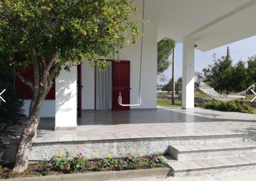 a white house with a red door and a tree at Villa Caporotondo in Pisticci