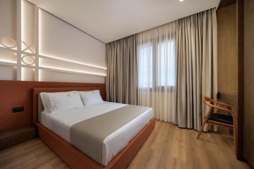 una camera da letto con un letto, una sedia e una finestra di Tic Tac Toe Residence a Durrës