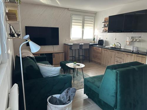 a living room with two green couches and a kitchen at Snow Lake in Divčibare