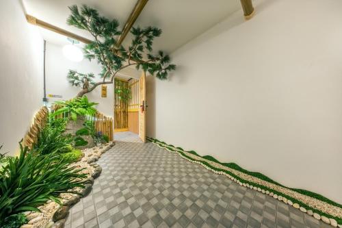 a hallway with a walkway with plants and a door at SHIN Hotel 80th Stadium Korat in Sathani Phu Khao Lat