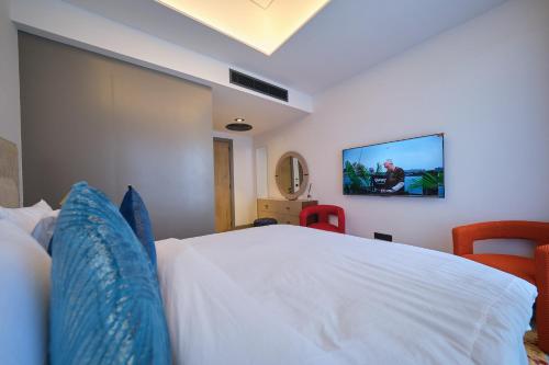 a bedroom with a white bed with a tv on the wall at The Diamond In City Luxury Suites By ZENORA Living in Accra