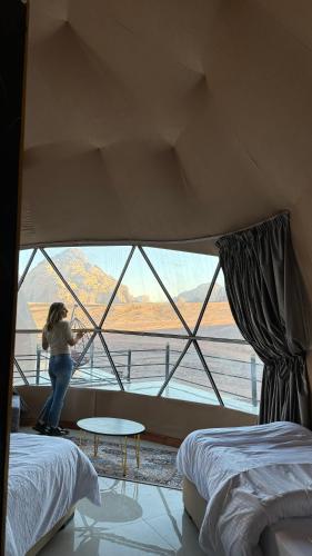 a woman standing in a room with a large window at Rum Rhal Luxury Camp in Aqaba