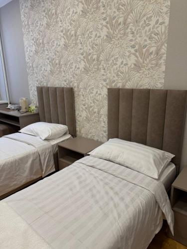 a bedroom with two beds and a wall at Hotel 002 in Osh