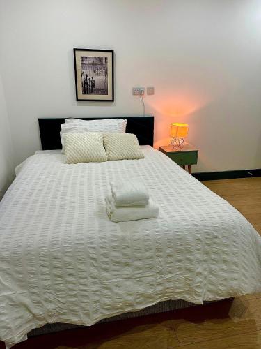 a large white bed with two towels on it at Stylish Ensuit Studios in the Heart of Vibrant Tooting 1 Min to Tube in London