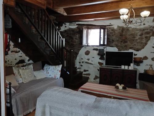 ein Wohnzimmer mit einem Sofa, einem TV und einer Treppe in der Unterkunft Rincón del Bierzo in Borrenes