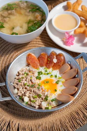 een bord eten met een ei, worst en frietjes bij Chavallee Campground in Ban Tha Chang