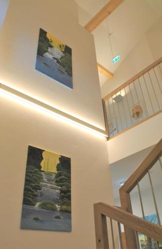 a hallway with two paintings on the wall and a staircase at Hotel Mauernböck in Rottenbach