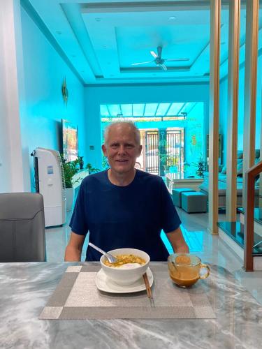 a man sitting at a table with a bowl of food at Muong Thanh Homestay in Diện Biên Phủ