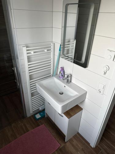 a white bathroom with a sink and a mirror at Creek House in Müllheim