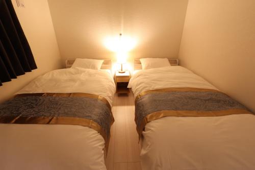 two beds in a small room with a light between them at Saifu Matsu - Vacation STAY 52738v in Dazaifu