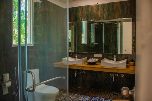 a bathroom with two sinks and a toilet and a mirror at Baagh-Bohemian 6BHK Farmhouse, Jagatpura, Jaipur in Jaipur