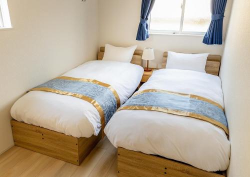 two beds in a small room with blue curtains at Saifu Ume - Vacation STAY 52782v in Dazaifu