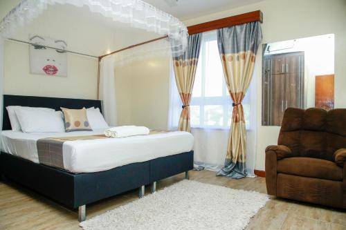 a bedroom with a canopy bed and a chair at Shanzu Beach Homes Mombasa in Mombasa