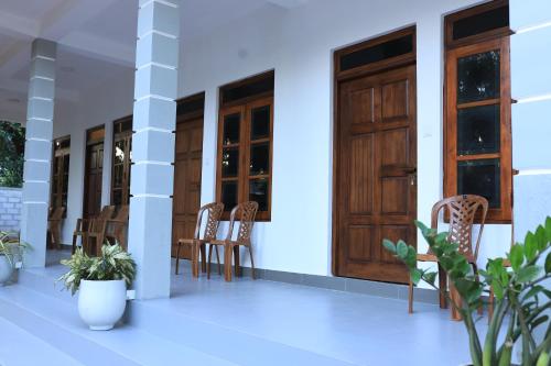 a porch of a house with wooden doors and chairs at Villa ONE66 in Dambulla