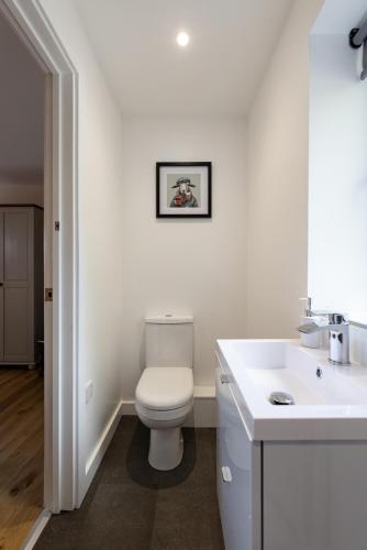 a white bathroom with a toilet and a sink at Meadow Roost York in York