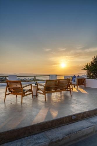 a group of benches sitting on a roof with the sunset at Athera Suites Mykonos in Tagou