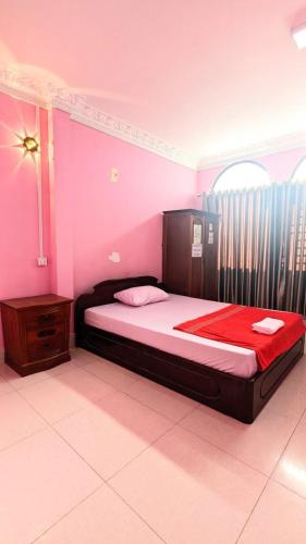 a bedroom with a bed in a pink room at Sampheap Guesthouse in Stœ̆ng Trêng